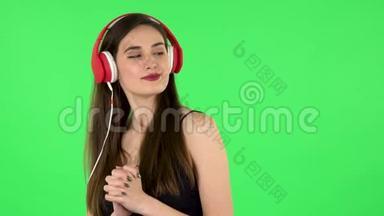 快乐的女孩跳舞，享受音乐在<strong>大</strong>红色耳机。 绿色屏幕